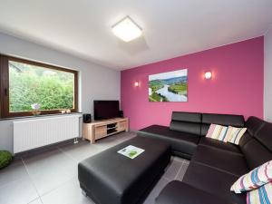 a living room with a black couch and a pink wall at Holiday home Moselle valley in Maring-Noviand