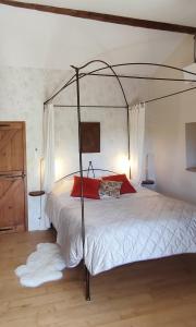 a bedroom with a canopy bed with white sheets and red pillows at Cyprès du château in Le Barroux
