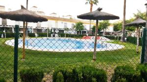una recinzione con ombrelloni di fronte alla piscina di Chalet Adosado con dos terrazas y piscina a La Antilla