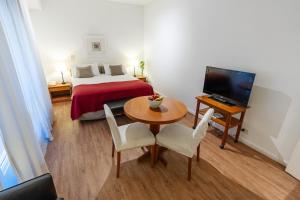 a room with a bed and a table and a television at Loi Flats Buenos Aires in Buenos Aires