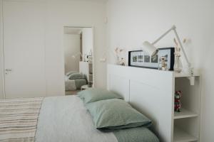 a white bedroom with a bed with green pillows at Sea & Rocks 15 - House in Lagoa
