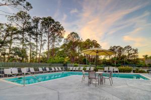 a pool with chairs and a table with an umbrella at HH Beach & Tennis 344B in Hilton Head Island