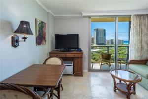 Una sala de estar con un televisor y una mesa y sillas. en Luana Waikiki Oceanview High Floor Condo 1210, en Honolulu