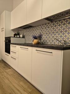 a kitchen with white cabinets and a black counter top at Domu MariaLuisa in Selargius