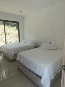 two beds in a room with a window at Casa Mezcal in Villeta +30 photos