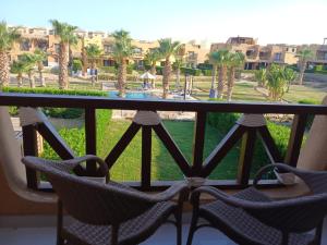 艾因苏赫纳Mountain View Sokhna 1, Villa 4 Bedrooms, Direct to Pool, 300 M to Beach & Dayra Camp, Families ONLY的阳台配有椅子,享有棕榈树的景致。