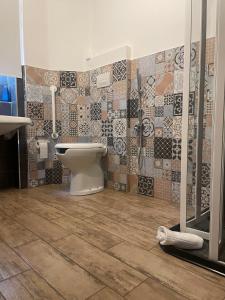 a bathroom with a toilet and tiles on the wall at Itaka in LʼAquila