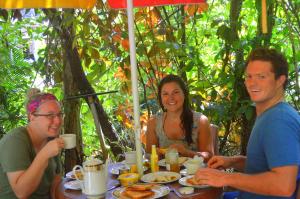 eine Gruppe von Menschen sitzt mit Essen um einen Tisch herum in der Unterkunft Haniffas Holiday Inn in Kandy