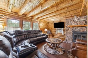 a living room with a leather couch and a fireplace at 8BR 5BA Huge Dog Friendly Log Cabin near Wisconsin Dells and Lake sleeps 25plus in Mauston