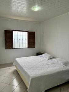 ein Schlafzimmer mit einem weißen Bett mit einem Fenster in der Unterkunft Casa mobiliada em Viçosa do Ceará em condomínio in Viçosa do Ceará