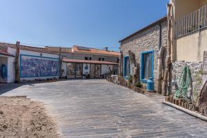 a stone walkway between two buildings with paintings on them at Cantinho do Bairro Alto in Alijó