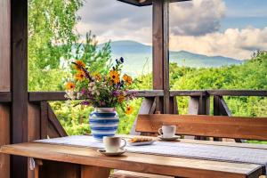 a table with a vase of flowers and two cups at Bieszczadzki Domek z widokiem na połoniny in Wetlina