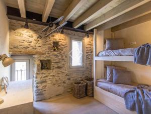 a room with two bunk beds and a stone wall at Villa Age con chimenea in Age