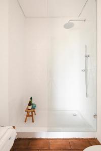 a white bathroom with a tub and a wooden stool at Vagar do Pastor in Alandroal