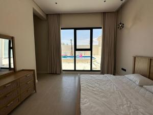 a bedroom with a bed and a view of a pool at شاليهات رزانه الفندقية in Ilbaras +22 photos