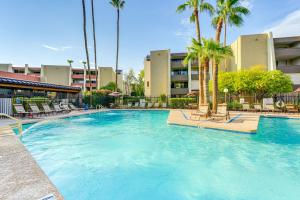 スコッツデールにあるWalkable Scottsdale Condo with Pool Access!のヤシの木と椅子が備わる大型スイミングプール
