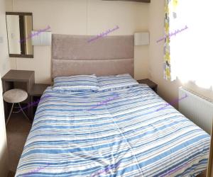 ein Bett mit einer blau-weiß gestreiften Bettdecke in einem Schlafzimmer in der Unterkunft Regal, West Sands, Seal Bay Resort, Selsey in Selsey + 36 Fotos