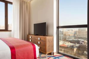 a bedroom with a television on a dresser with a window at Ramada Hotel & Suites by Wyndham Yerevan in Yerevan