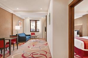 a hotel room with a bed and a table and chairs at Ramada Hotel & Suites by Wyndham Yerevan in Yerevan