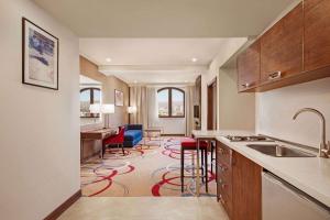 a kitchen with a sink and a living room at Ramada Hotel & Suites by Wyndham Yerevan in Yerevan