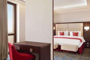 a bedroom with a large bed and a red chair at Ramada Hotel & Suites by Wyndham Yerevan in Yerevan