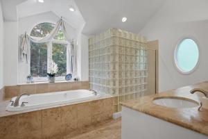 baño con bañera, 2 lavabos y ventana en Luxurious Private Lakefront Paradise home, en Mooresville