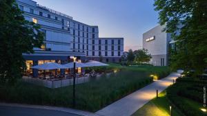 ein Gebäude mit Tischen und Sonnenschirmen davor in der Unterkunft Dorint Parkhotel Frankfurt / Bad Vilbel in Bad Vilbel