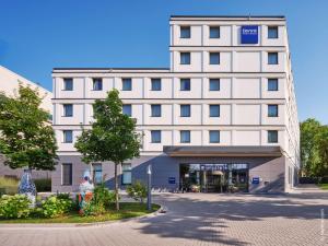 ein weißes Gebäude mit einem Weihnachtsbaum davor in der Unterkunft Dorint Parkhotel Frankfurt / Bad Vilbel in Bad Vilbel
