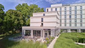 ein weißes Gebäude mit einem Garten davor in der Unterkunft Dorint Parkhotel Frankfurt / Bad Vilbel in Bad Vilbel