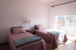 a bedroom with two beds with pink sheets and a window at Departamento de lujo in Tarija
