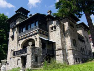 an old stone building with a statue on top of it at Casa Cu Farfurii in Sinaia