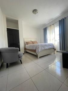 una camera da letto con un letto e una sedia di Weekendz- Cozy 2BRD Suite a Port Antonio
