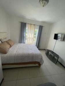 una camera da letto con un letto e una grande finestra di Weekendz- Cozy 2BRD Suite a Port Antonio Altre 5 foto