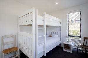 a bedroom with a white bunk bed and a window at Wanakas home away from home in Wanaka