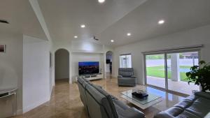 a living room with a couch and a tv at Sunny Oasis with private pool in Homestead
