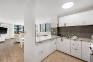 Una cocina con gabinetes blancos y una sala de estar. en Beachfront Beauty - Cooly, en Gold Coast