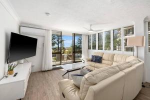 Una sala de estar con un sofá y un televisor de pantalla plana. en Beachfront Beauty - Cooly, en Gold Coast
