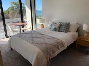 a bedroom with a bed with a view of the ocean at Guest Suite with Sea Views and Thermally Heated Hot Tub in Tauranga