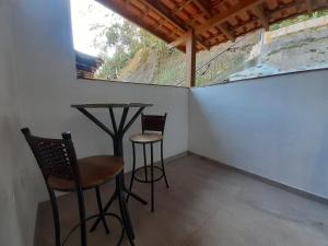 una pequeña mesa y sillas en una habitación con ventana en Suíte independente próxima ao centro histórico de Petrópolis, en Petrópolis