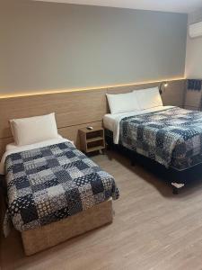 ein Hotelzimmer mit zwei Betten und einem Nachttisch in der Unterkunft Jardim Paulista Apartamento com Vista in São Paulo