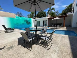 a table with chairs and an umbrella next to a pool at advengers Bucerias Nayarti in Bucerías