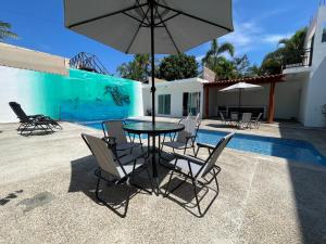 a table with chairs and an umbrella next to a pool at advengers Bucerias Nayarti in Bucerías +2 photos