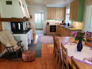 a kitchen with a dining table and a kitchen with green cabinets at Landlig idyll 200 meter fra sjøen in Lillesand