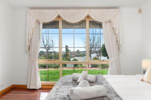 une chambre avec une grande fenêtre et un grand lit dans l'établissement Coastal Comfort 4BR Vacation Home in Hallett Cove, à Halletts Cove