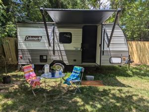 a caravan with two chairs and a table in front of it at Cozy Camper RV in Statesville in Statesville