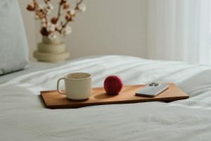 a tray with a coffee cup and an apple on a bed at Apartment B8 "Workation, Sauna & Fitness" im Pine Hill Resort in Zirchow