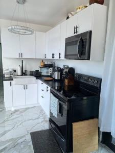 a kitchen with white cabinets and a black stove top oven at ONE BEDROOM Ocean- Mountain View home five min to beach in Luquillo
