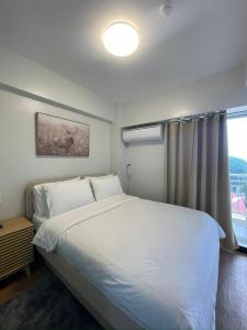 a bedroom with a large white bed and a window at 1 BR Condo with balcony in Verdon Parc Trevans Building in Davao City
