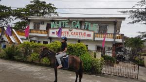 a woman riding a horse in front of a building at White Castle Beach Resort in Iba