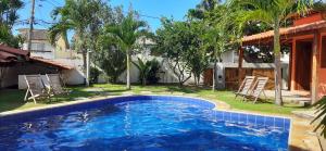a swimming pool in a yard with chairs and a house at Villa Tropicale in Salvador